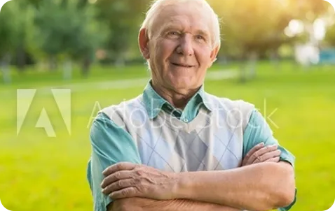 An old man with his arms crossed in a park.