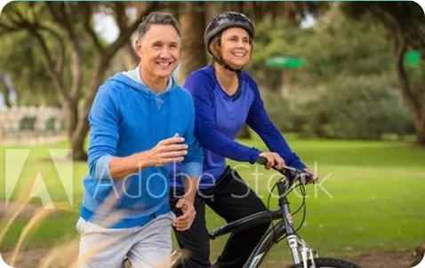 Two people on bicycles in a park with trees