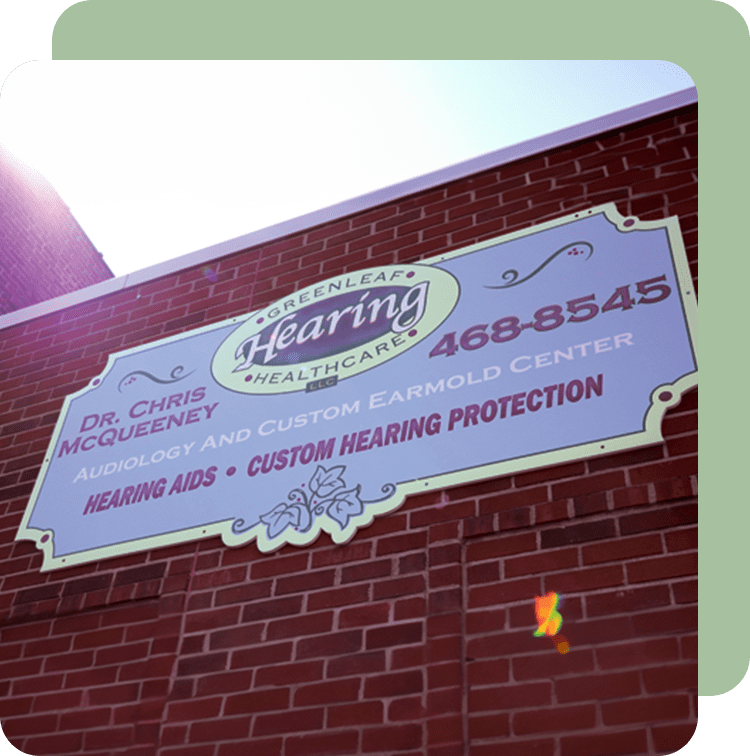 A sign on the side of a building that says hearing aids and custom hearing protection.